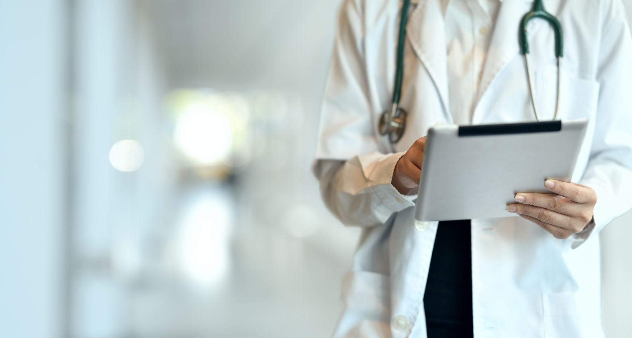 Detailní záběr na mladou profesionální lékařku, která pomocí tabletu shrnuje zdravotní dokumentaci pacienta v nemocnici.